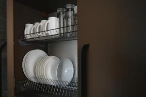 Aperto cassetti con diverso piatti e ciotole nel cucina, avvicinamento foto