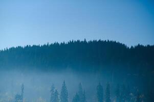 montagna gamma con visibile sagome attraverso il mattina blu nebbia. foto