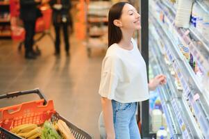 contento giovane donna guardare a Prodotto a drogheria negozio. sorridente donna shopping nel supermercato foto