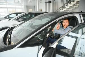 giovane uomo, vendita elettrico macchine nel il showroom. concetto di acquisto eco-friendly auto per famiglia foto