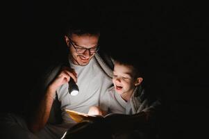 padre e il suo poco figlio lettura di andare a dormire storia a casa. foto