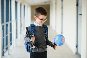 scolaro con cartella e libri nel il scuola. formazione scolastica concetto. indietro per scuola. schoolkid andando per classe. elegante ragazzo con zaino. ragazzo pronto per studia. foto