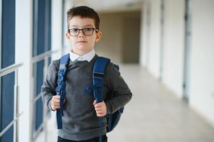 scolaro con cartella e libri nel il scuola. formazione scolastica concetto. indietro per scuola. schoolkid andando per classe. elegante ragazzo con zaino. ragazzo pronto per studia. foto