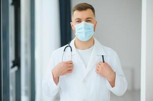 medico uomo mette su un' protettivo maschera foto