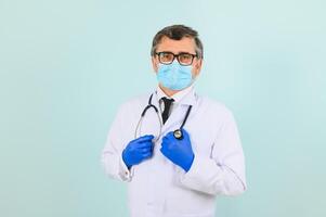 uomo nel medico guanti mettendo su protettivo viso maschera contro blu sfondo. foto