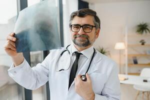 più vecchio uomo medico esamina raggi X Immagine di polmoni nel un' clinica foto