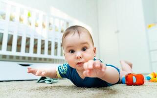 un' tranquillo, calmo bambino riposo su il pavimento. un' bambino posa su il pavimento nel un' camera foto