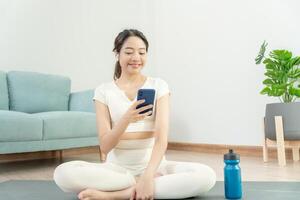 sottile donna uso Telefono e sentire ricreazione su yoga attività. asiatico donna esercizi nel mattina. equilibrio, meditazione, rilassamento, calma, bene Salute, felice, relax, salutare stile di vita, dieta, sottile foto