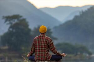 posteriore Visualizza di uomo è rilassante praticante meditazione yoga nel foresta nel estate per raggiungere felicità a partire dal interno pace saggezza con mattina leggero per salutare mente e anima concetto foto