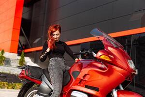 un avventuroso donna godendo un' cavalcata su un' vivace rosso motociclo contro un' pittoresco sfondo. foto