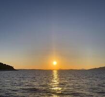 tramonto al di sopra di il mare con un' barca nel il distanza foto