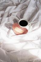 fatto a mano san valentino cuore e caffè tazza su letto. accogliente San Valentino giorno mattina. foto