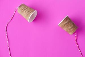 Fai da te carta tazze con corda su rosa sfondo. concetto, telefono giocattoli quale applicare con scienza conoscenza di vibrazione suono attraverso sforzando stringhe causando noi per sentire il suono. foto