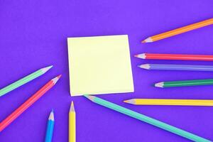 colore matite e carta bloc notes su viola sfondo. concetto, educativo materiali, arte. assunzione Nota, rendere piani, promemoria. foto