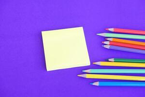 colore matite e carta bloc notes su viola sfondo. concetto, educativo materiali, arte. assunzione Nota, rendere piani, promemoria. foto