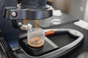 caldo caffè espresso è versato a partire dal il caffè macchina. foto