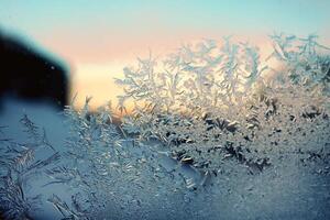 brina modello su finestra bicchiere nel inverno freddo blu leggero con arancia e rosa scorci di tramonto. Natale e nuovo anno sfondo. foto