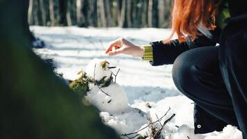 donna la creazione di pupazzo di neve sotto spoglio alberi foto
