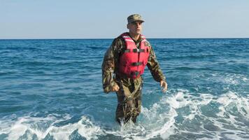 soldato con vita giacca arriva su di il mare foto