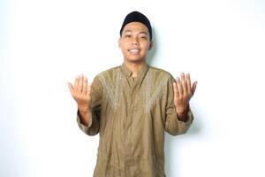 sorridente musulmano asiatico uomo godere preghiere nel Ramadhan indossare islamico Abiti isolato su bianca sfondo foto