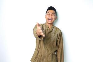gioioso asiatico musulmano uomo offerta stretta di mano con ridendo isolato su bianca sfondo foto
