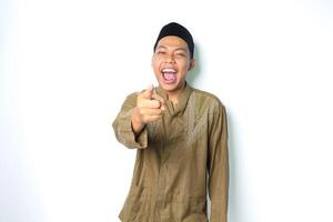 eccitato asiatico musulmano uomo urlando con puntamento a telecamera indossare islamico vestito isolato su bianca sfondo foto