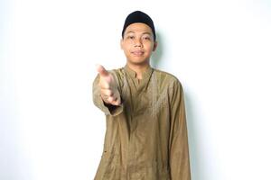 tranquillo, calmo asiatico musulmano uomo offerta stretta di mano a telecamera isolato su bianca sfondo foto