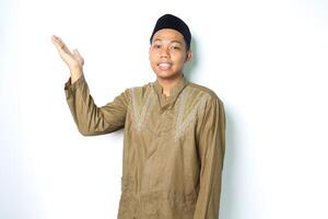 sorridente asiatico musulmano uomo indossare islamico vestito presentazione vuoto spazio isolato su bianca sfondo foto
