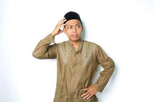 riflessivo asiatico musulmano uomo pensiero sul serio con toccante il suo testa indossare koko Abiti isolato su bianca sfondo foto