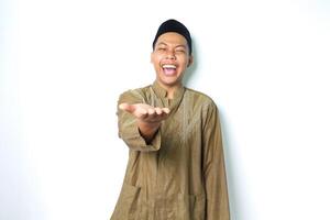 estatico asiatico musulmano uomo indossare islamico vestito raccolta palma a telecamera per presentazione con ridendo espressione isolato su bianco sfondo foto