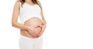 donna incinta che fa la forma del cuore con le mani sulla pancia - immagine ritagliata. foto