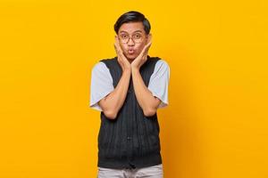 ritratto di giovane uomo asiatico sorpreso che guarda l'obbiettivo isolato su sfondo giallo foto