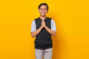 Ritratto di felicità giovane uomo asiatico che tiene la mano su supplica su sfondo giallo