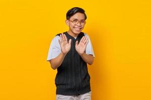 giovane uomo asiatico facendo gesto di arresto con i palmi delle mani isolate su sfondo giallo foto