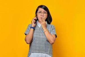 sorpresa giovane donna asiatica nel ricevere una chiamata in arrivo sul telefono cellulare e coprendo la bocca con la mano foto