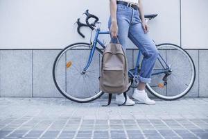 sezione bassa giovane donna in piedi vicino a una bicicletta con in mano uno zaino? foto