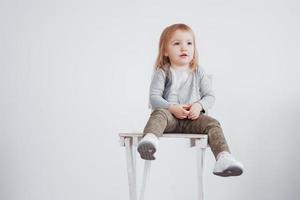 un bambino, una bambina seduta su uno sgabello alto che ride