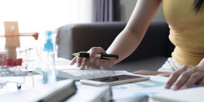 mano ravvicinata della donna che utilizza il computer calcolando le finanze domestiche o le tasse sulla macchina, la donna gestisce le spese familiari domestiche, utilizza la calcolatrice, effettua il pagamento sul laptop foto