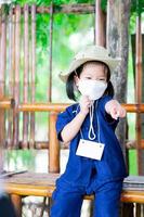 una ragazza carina indossa una maschera chirurgica bianca per prevenire la diffusione del virus e piccole polveri tossiche pm2.5. bambino che punta le dita in avanti rispondendo con sicurezza alle domande.