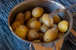 un' cucinando pentola con non pelati cucinato patate foto