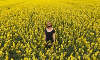 un' ragazza nel un' nero vestito tra il colori di stupro nel il campo. w foto