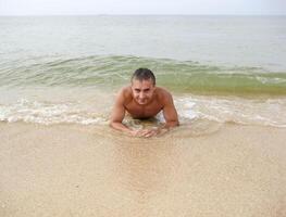 uomo su il riva bugie. il mare onda coperture il maschile. spiaggia foto