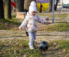 il bambino è giocando con il sfera. un' poco quattro anni ragazza giochi con un' calcio. foto