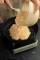 fabbricazione okonomiyaki frutti di mare pancake con prosciutto, gamberetto, e verdura foto