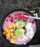 es tele, indonesiano dolce fatto a partire dal molti genere di tropicale frutta, condensato latte con dolcificante sciroppo e ghiaccio cubo. servito su bianca ciotola e posto su il vecchio di legno tavolo. selettivo messa a fuoco foto