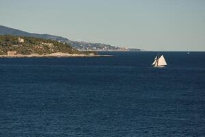 monaco, enorme vela yacht è nel mare a tramonto, isola è qui vicino, ricchezza vita di miliardari, montagne su sfondo foto