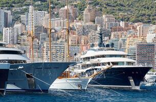 pochi enorme lusso yachts a il famoso motoscafo esposizione nel il principato di monaco, monte Carlo, il maggior parte costoso Barche per il il più ricco le persone, montagna e Residenziale complesso su sfondo foto