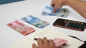 un' uomo è conteggio indonesiano rupia banconote. finanziario gestione concetto foto