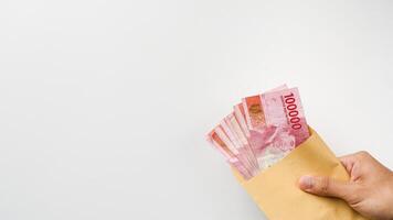 mano Tenere rupia i soldi nel un' Marrone Busta. indonesiano moneta foto
