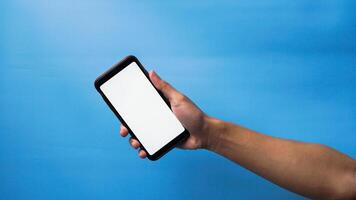 mano di uomo Tenere mobile smartphone e mostrando vuoto Telefono schermo su blu sfondo foto